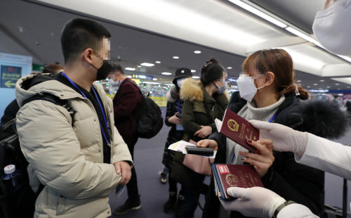 인천국제공항 1터미널에서 지난 5일 중국발 여객기를 타고 도착한 승객들에게 공항 관계자들이 검역대에서 걷은 여권을 나눠주고 있다. 사진=연합뉴스