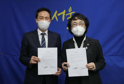 더불어민주당 우상호 의원(왼쪽)과 열린민주당 김진애 의원이 12일 국회에서 만나 양당 후보 단일화 추진 내용을 담은 합의문에 서명한 모습. 사진=열린민주당 제공