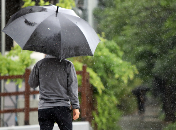 지난 6일 오후 대전 유성구 갑천에 장대비가 내리는 가운데, 시민들이 우산을 쓰고 발걸음을 재촉하고 있다. 대전은 지난 4일부터 이날 오후 1시까지 누적 강수량 104.5㎜를 기록했다. 사진=연합뉴스