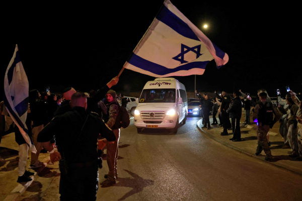 하마스에 납치된 뒤 풀려난 러시아인 인질 2명을 태운 차량이 이스라엘 오파킴을 지나는 가운데 29일(현지시간) 한 남성이 이스라엘 국기를 흔들고 있다. 오파킴 AFP=연합뉴스